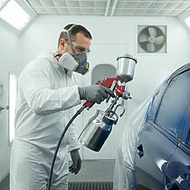 Ouvrier en combinaison utilisant le pistolet FINDER sur carrosserie.